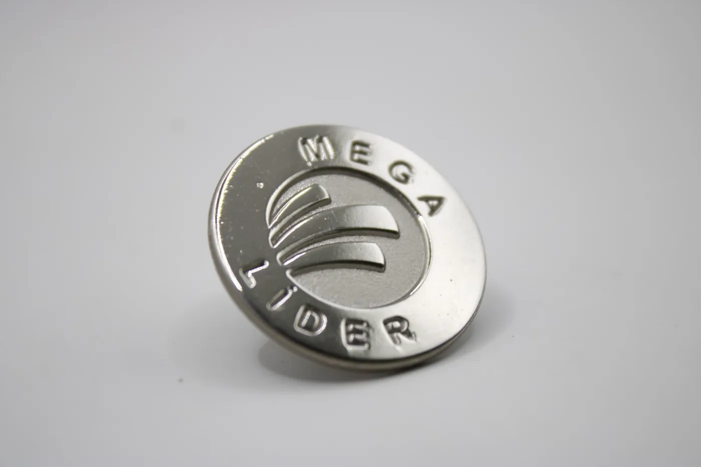 Pin circular plateado con logotipo grabado del programa Mega Líder