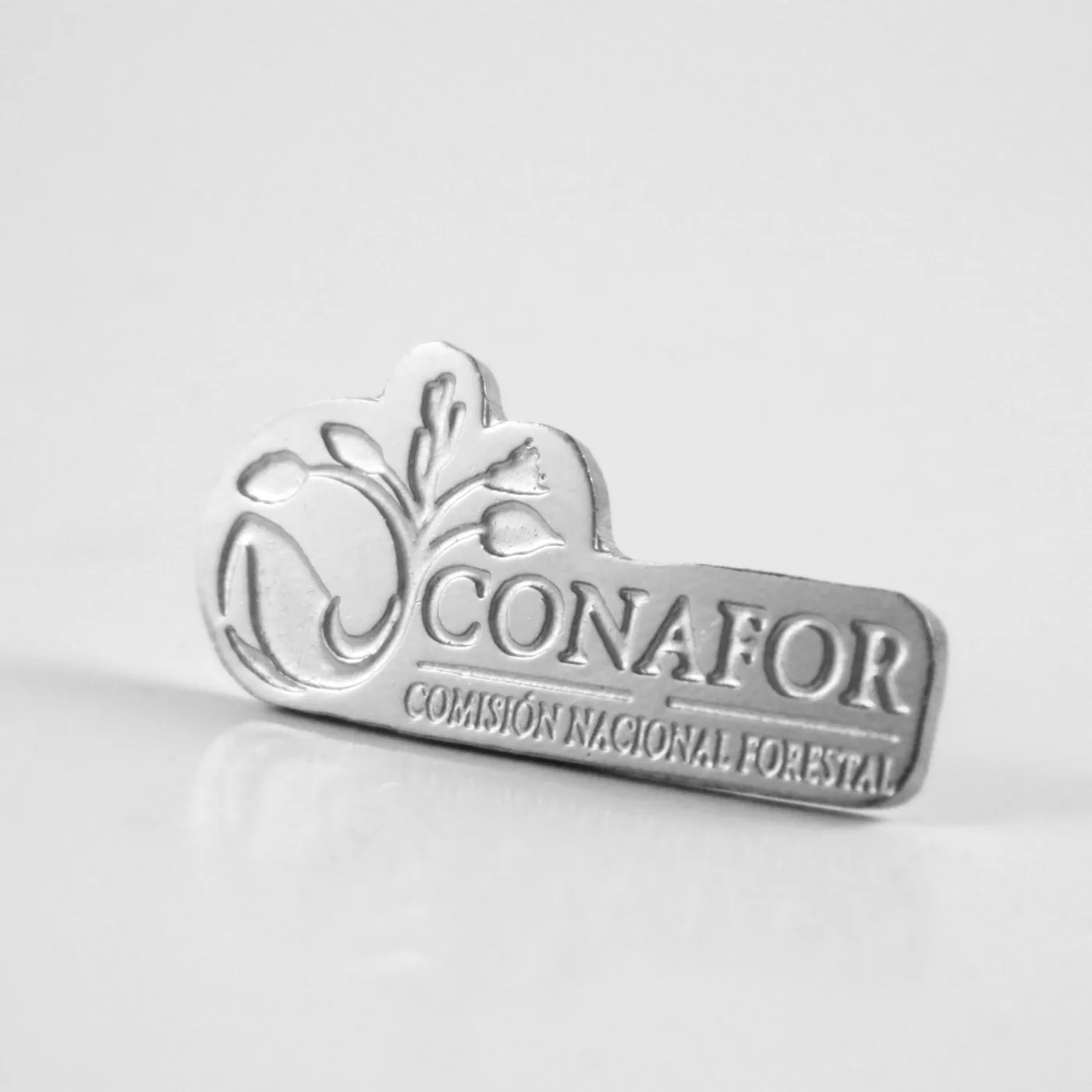 Pin institucional plateado con logotipo en relieve de la CONAFOR