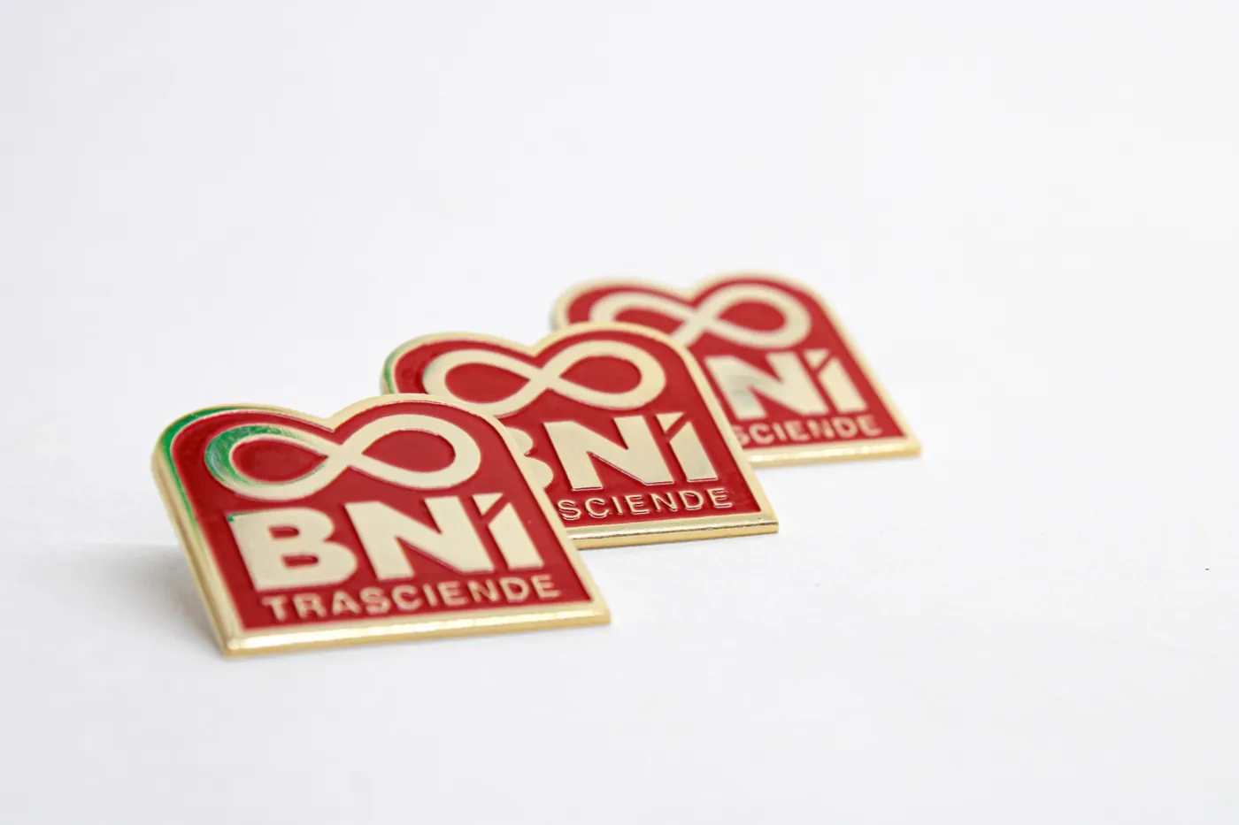 Pines rojos con logotipo BNI Trasciende y filo dorado