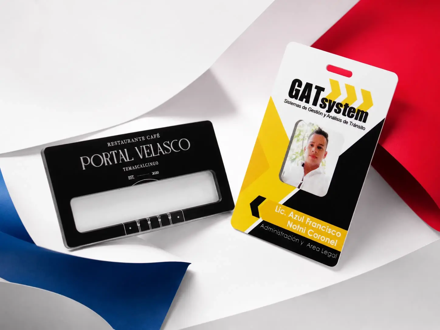 Gafete negro grabado y credencial a color sobre papel azul y rojo
